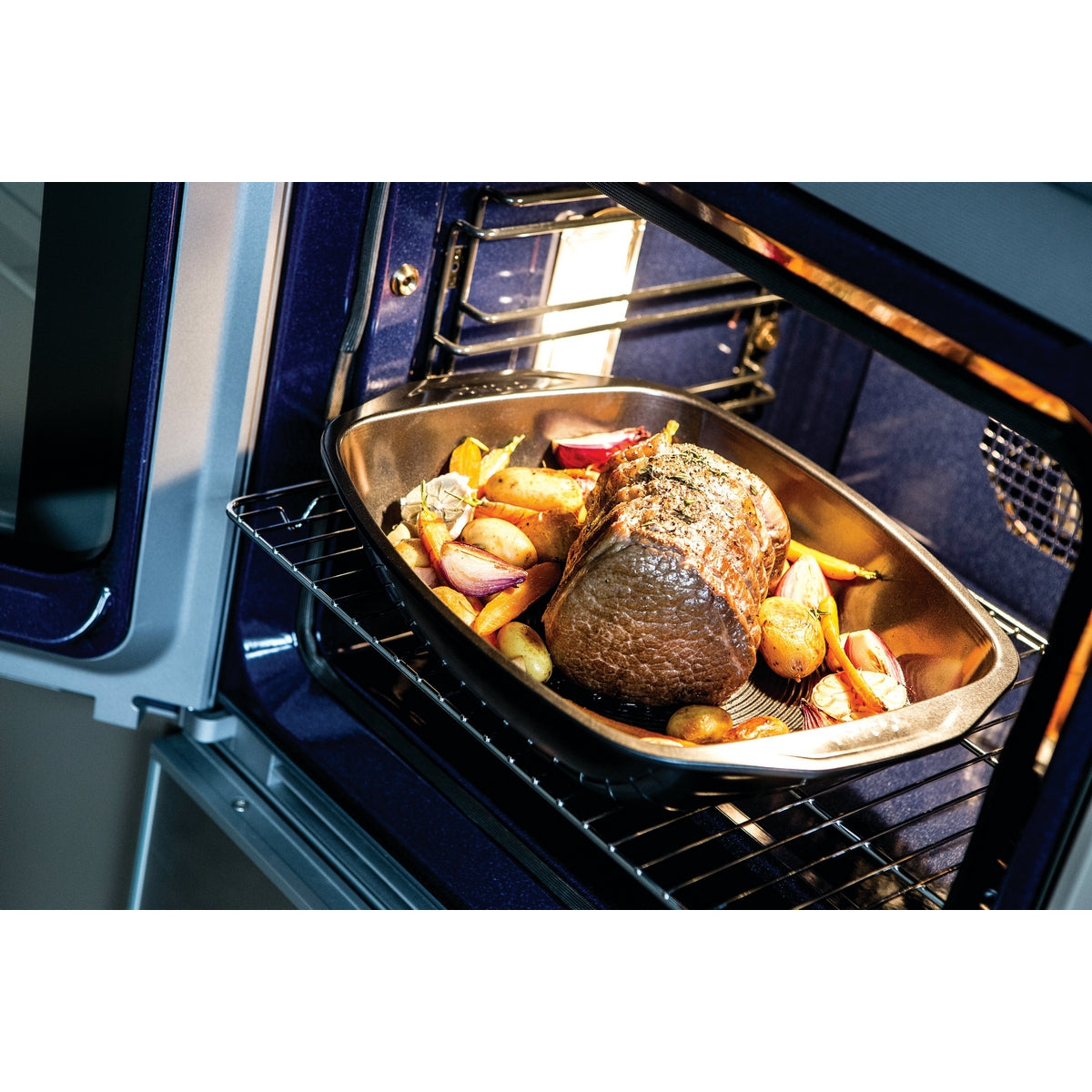 Roasting tray in oven with roast beef and vegetables.