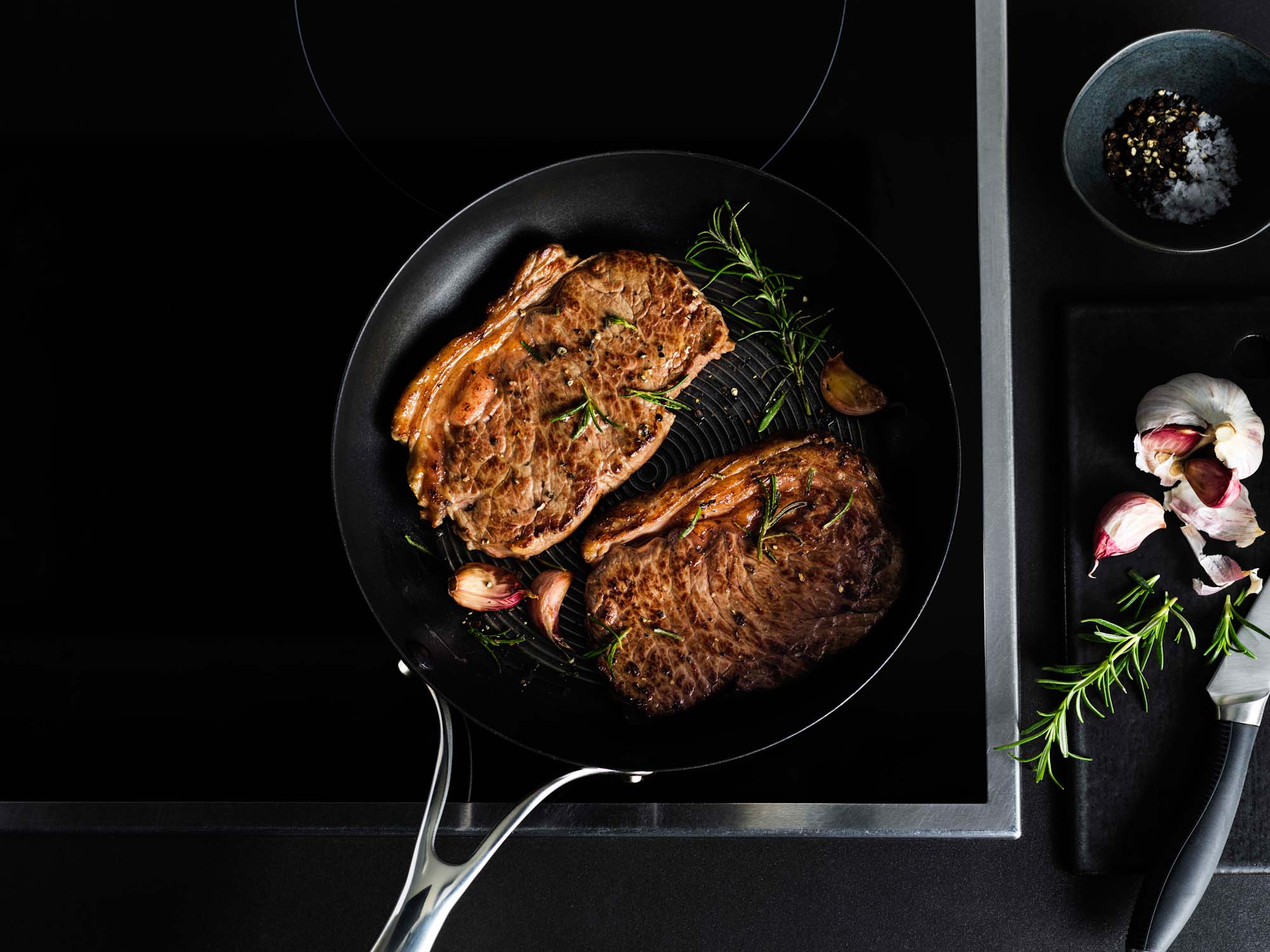 Steaks in a Circulon frying pan on an induction hob