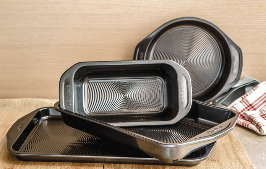 Two rectangular cake tins stacks at an angle on a baking tray, with a round cake tin in the background.