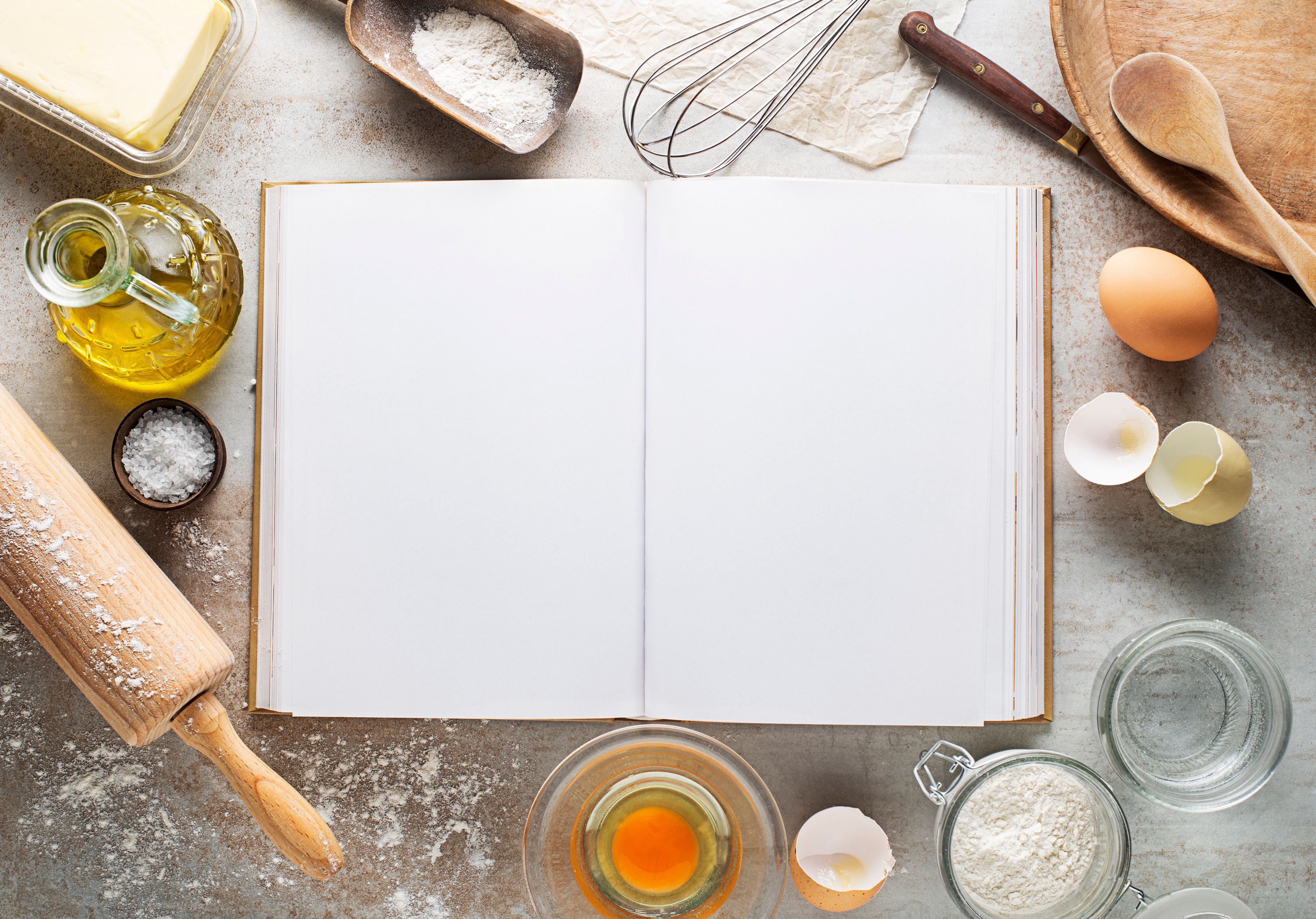 Open recipe book surrounded by baking ingredients. Page is blank, enticing the reader to find out what the nation's favourite homecooked recipe might be.