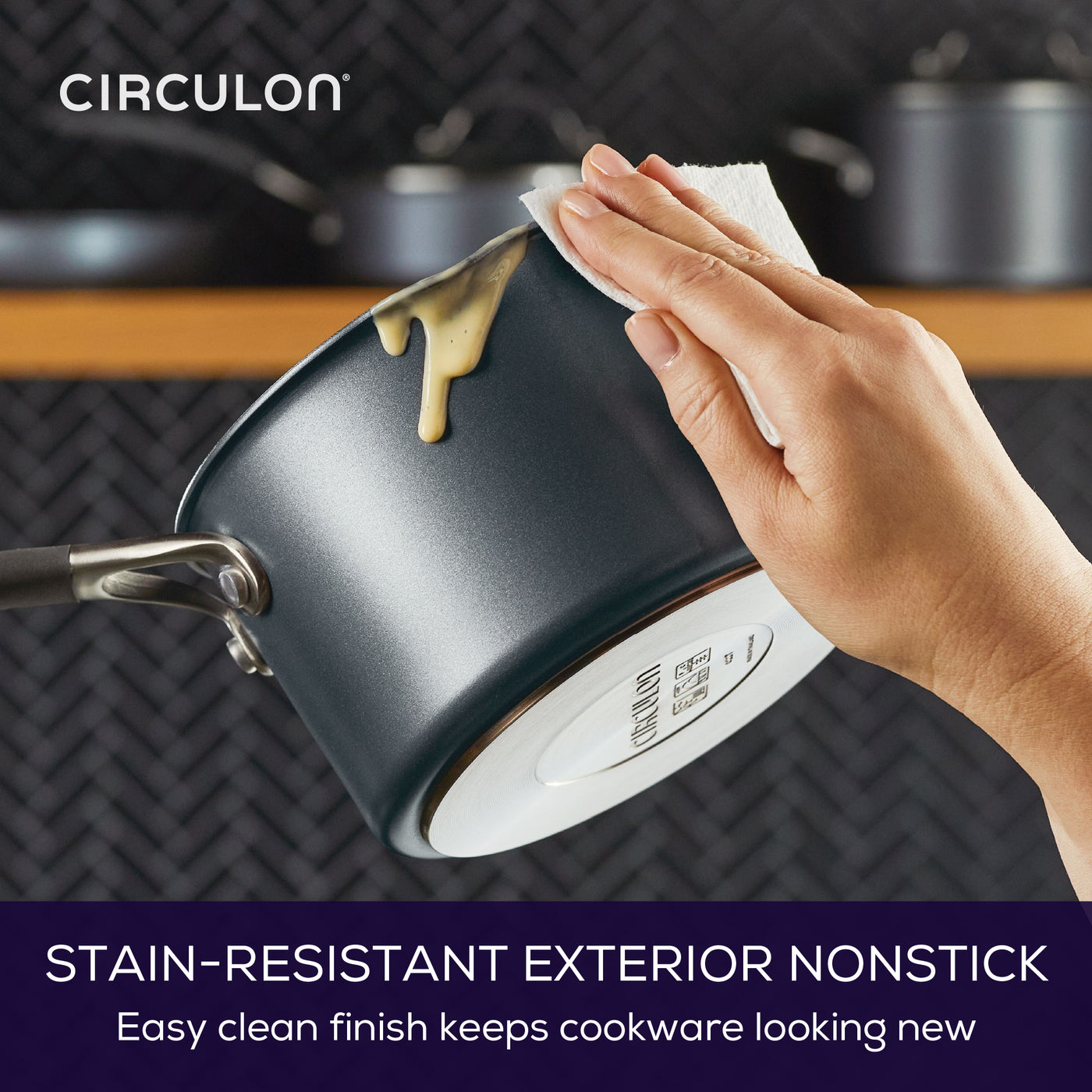 Image shows someone wiping drips from a saucepan with kitchen towel. Text reads: Stain-resistant exterior nonstick. Easy clean finish keeps cookware looking new.