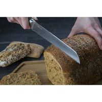 Bread knife cutting loaf of bread.