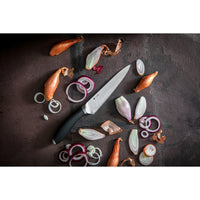 Image shows 6" Kitchen Knife with Japanese steel blade surrounded by sliced shallots on a dark background.